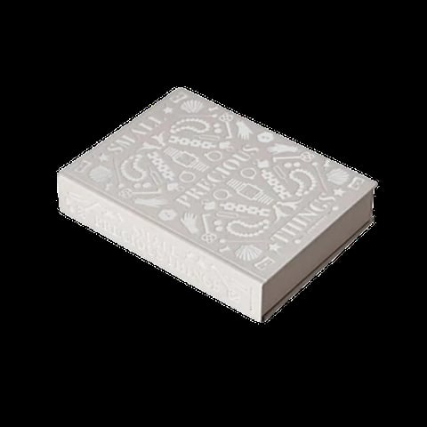 White book with ornate decorative pattern on cover, shown at an angled perspective against black background