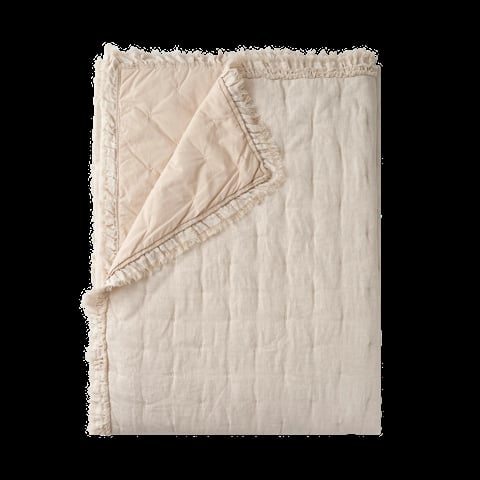 Cream-colored quilted bedspread or throw blanket with ruffled edges, partially folded