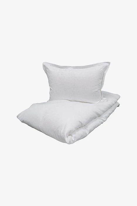 White pillow and folded duvet on light gray background, displayed as a bedding set