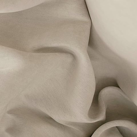 Close-up of soft, draped beige fabric with flowing folds and gentle shadows