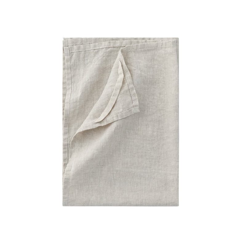 Folded beige linen cloth or tea towel with one corner curled upward on white background